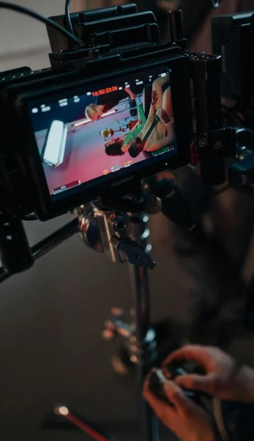 Close-up of a video camera setup with screen showing preview on set.