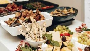 A mouth-watering assortment of cheeses, breadsticks, and fruits in a buffet setting. Perfect for catering events.