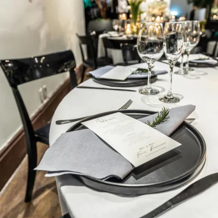 Elegant table setting with a menu and wine glasses, perfect for dinner events.