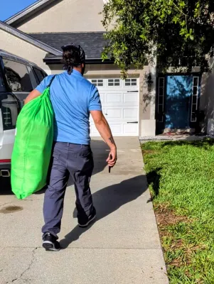 Pickup and delivery driver dropping off clean laundry at a residential porch.