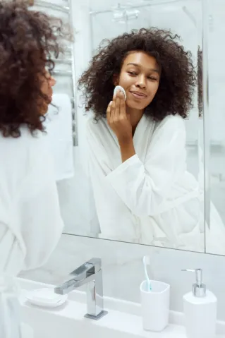 a woman applying makeup in the mirror