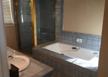 dark bathroom with grey/black tiles and white sink and bathtub