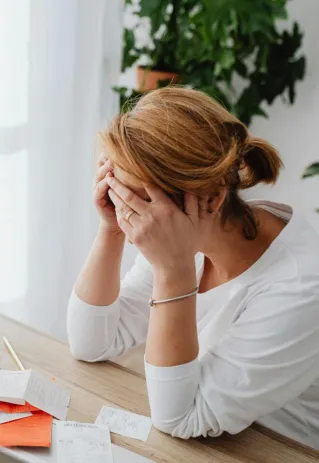 Woman stressed over financial receipts at a desk, dealing with expenses and calculations.