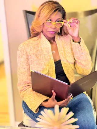 Selective Focus Photo of Smiling Woman in Yellow Shirt and Blue Jeans Carrying a Laptop