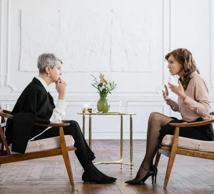 Two women engaged in a counseling session in a bright, modern loft setting.