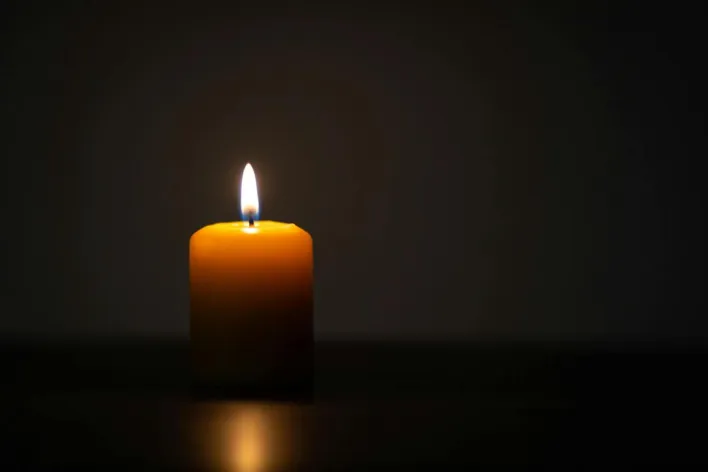 A single candle burns brightly in a dark room, symbolizing hope and tranquility.