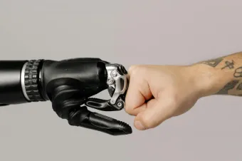 Close-up of a human fist bumping a prosthetic hand, symbolizing technology and human connection.