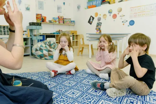 Kids Sitting on the Floor and Playing Game with Fingers on Eyes