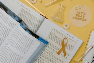 Flat lay of scientific research tools and gold ribbon for cancer awareness.