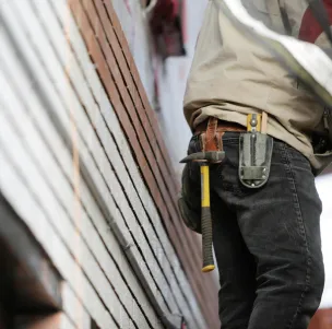 Close-up of a construction worker with hammer and tools, focused on the job.