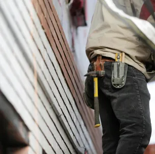Close-up of a construction worker with hammer and tools, focused on the job.