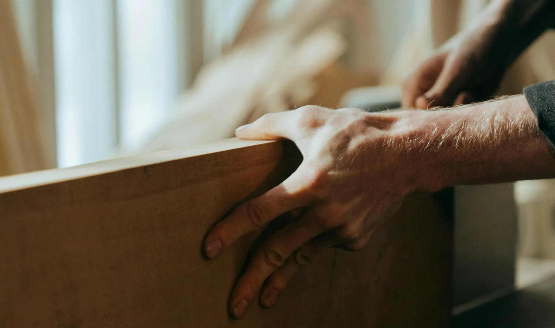 Close-up of a craftsman's hands working with wood in a workshop setting.
