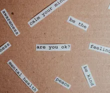 Cut-out words promoting mental health awareness on cardboard background.