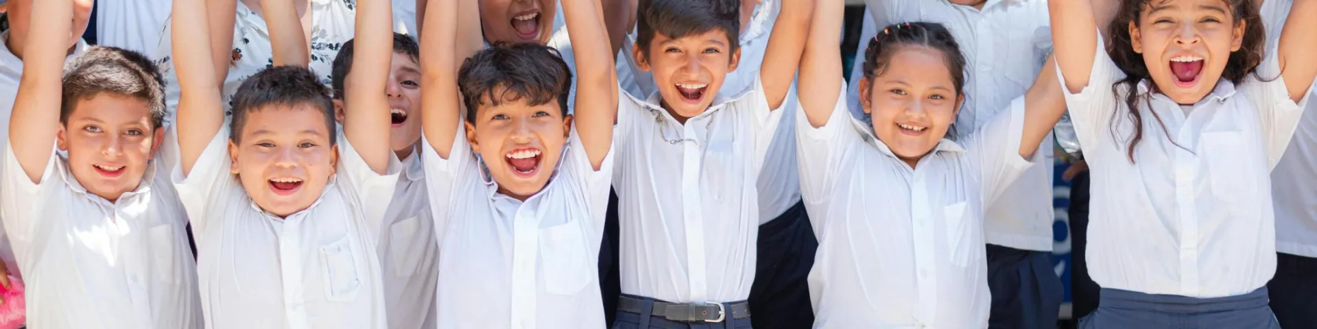 Joyful group of school children in Santa Rosa de Lima, El Salvador cheering outdoors.