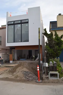Construction site o 3-story house with new stucco surface, roof deck and garage area without door or deck railing