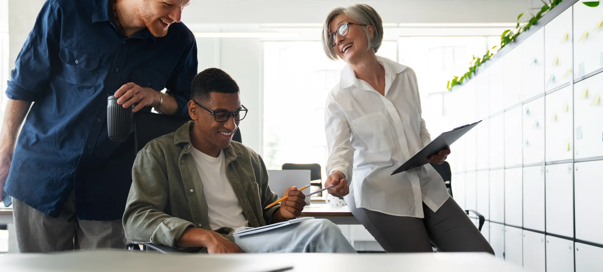 A diverse group of coworkers in a modern office engaged in teamwork using technology.