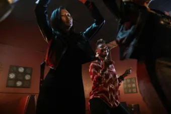 Women enjoying a lively dance indoors, hands raised, wearing trendy outfits.