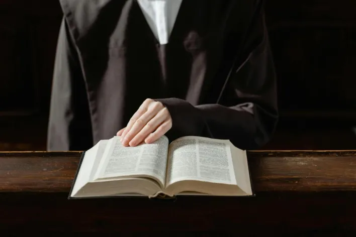 A person in religious attire reading an open Bible, highlighting the connection to spirituality.