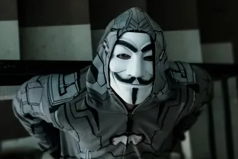 A person wearing a costume mask and hoodie standing on a staircase, creating a mysterious ambiance.