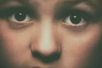 Detailed close-up of a child's face focusing on expressive brown eyes, conveying emotion.