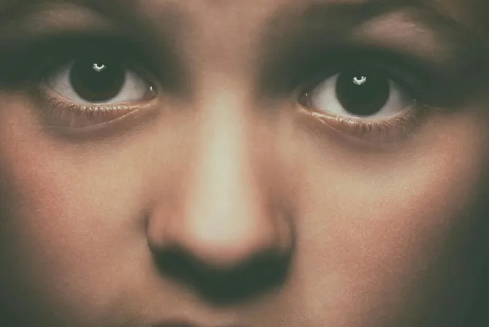 Detailed close-up of a child's face focusing on expressive brown eyes, conveying emotion.