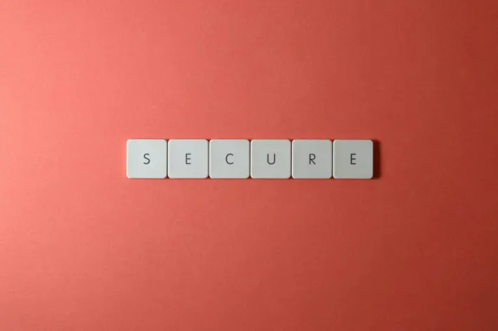 A close-up of the word 'Secure' spelled out with tiles on a red surface, ideal for security concepts.