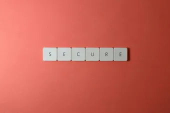 A close-up of the word 'Secure' spelled out with tiles on a red surface, ideal for security concepts.