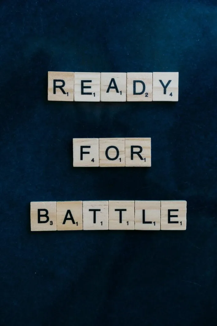 Wooden Scrabble tiles arranged to spell 'Ready for Battle' on a dark background.