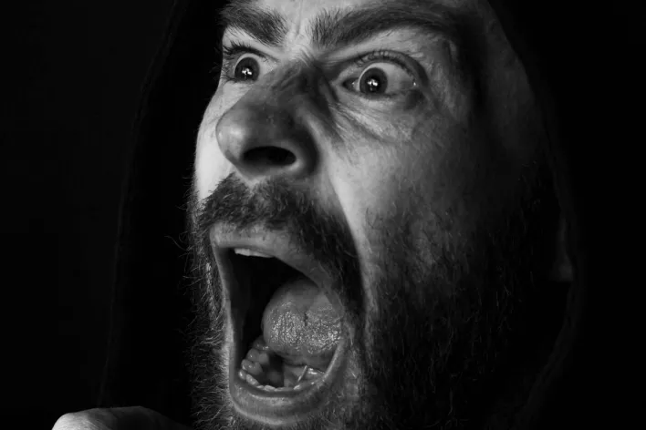 Dramatic black and white portrait of a man screaming with intense expression.
