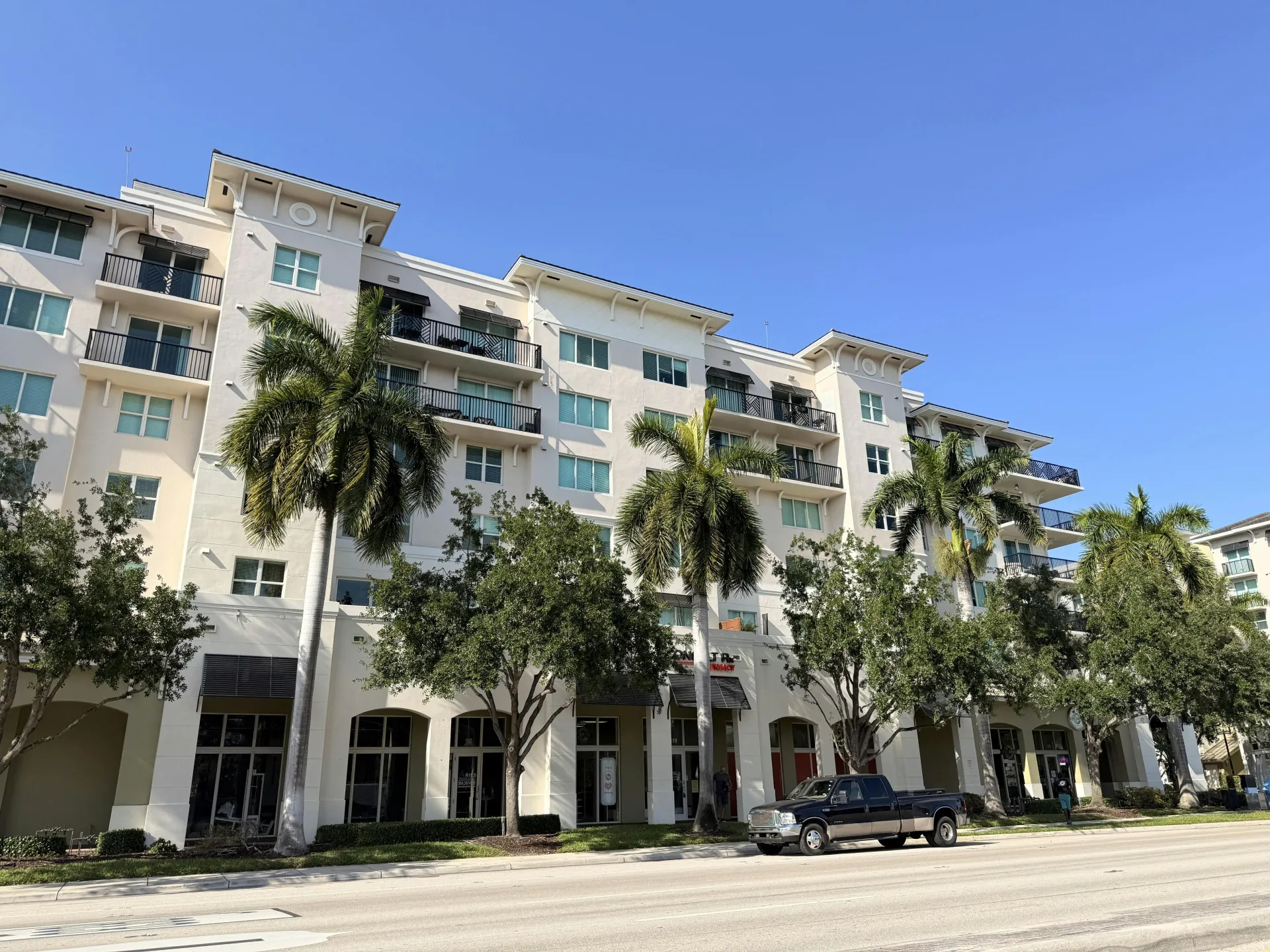 A modern apartment building with palm trees on a clear sunny day.