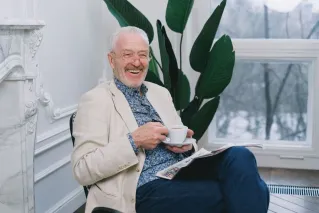 Cheerful senior man enjoying tea while relaxing indoors. Perfect depiction of leisure and contentment.
