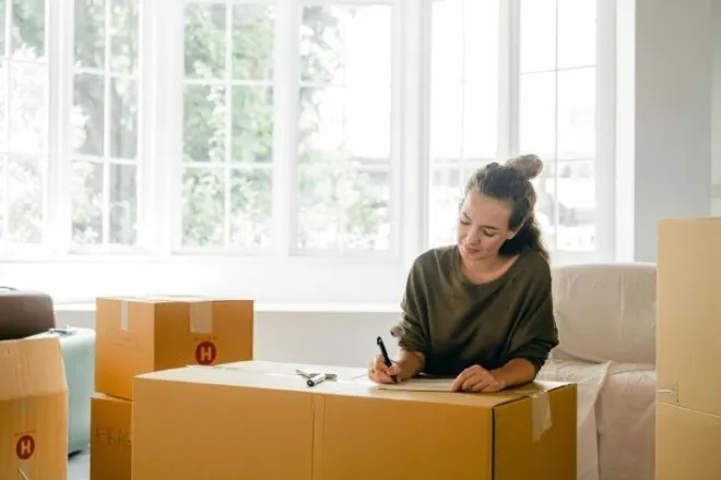 A Pop In Concierge happily organizing and labling boxes for a downsizing client
