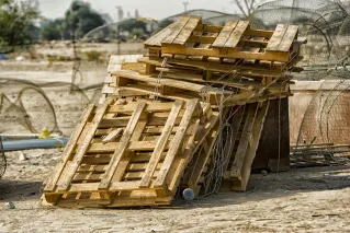 Rustic stack of wooden pallets with wire mesh outdoors in Al Jahra, Kuwait.