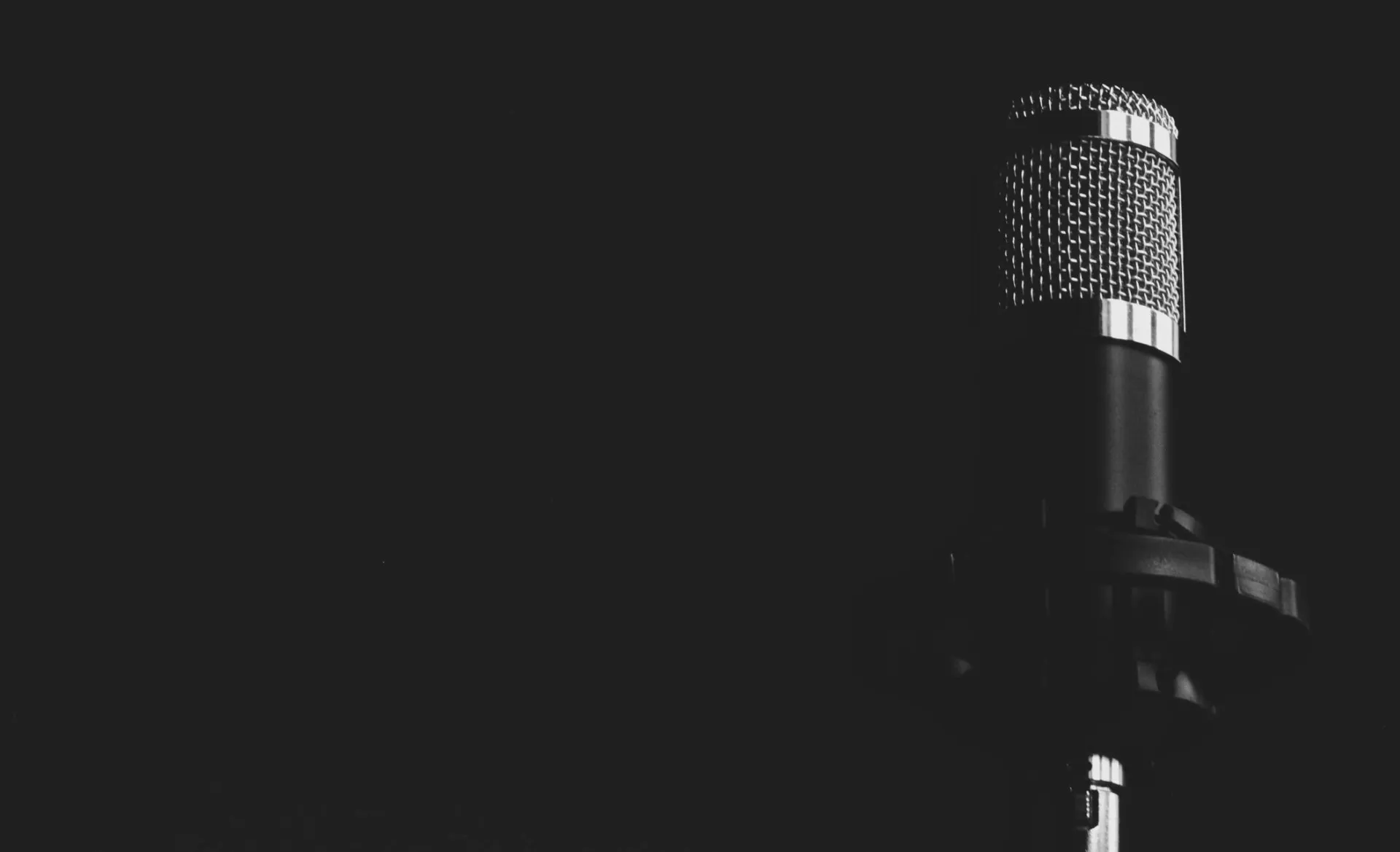 Close-up view of a studio microphone against a dark background, emphasizing audio technology.