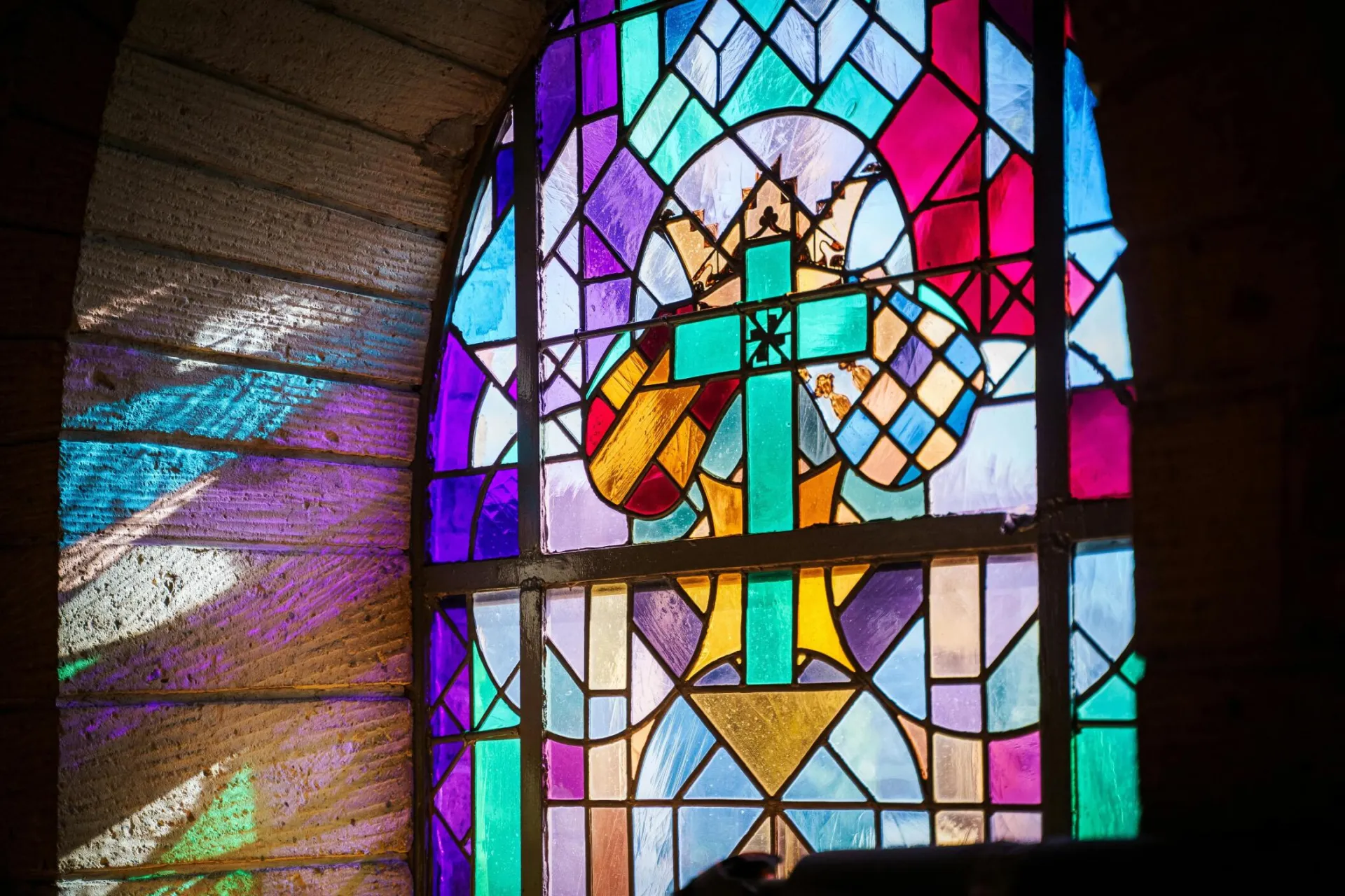 Colorful stained glass window with Christian symbolism in a church setting.