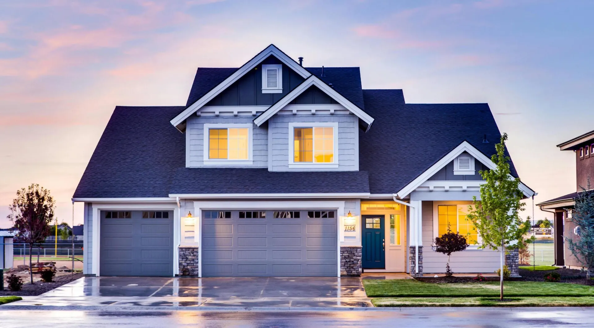 Beautiful two-story house with illuminated windows and garage at dusk.