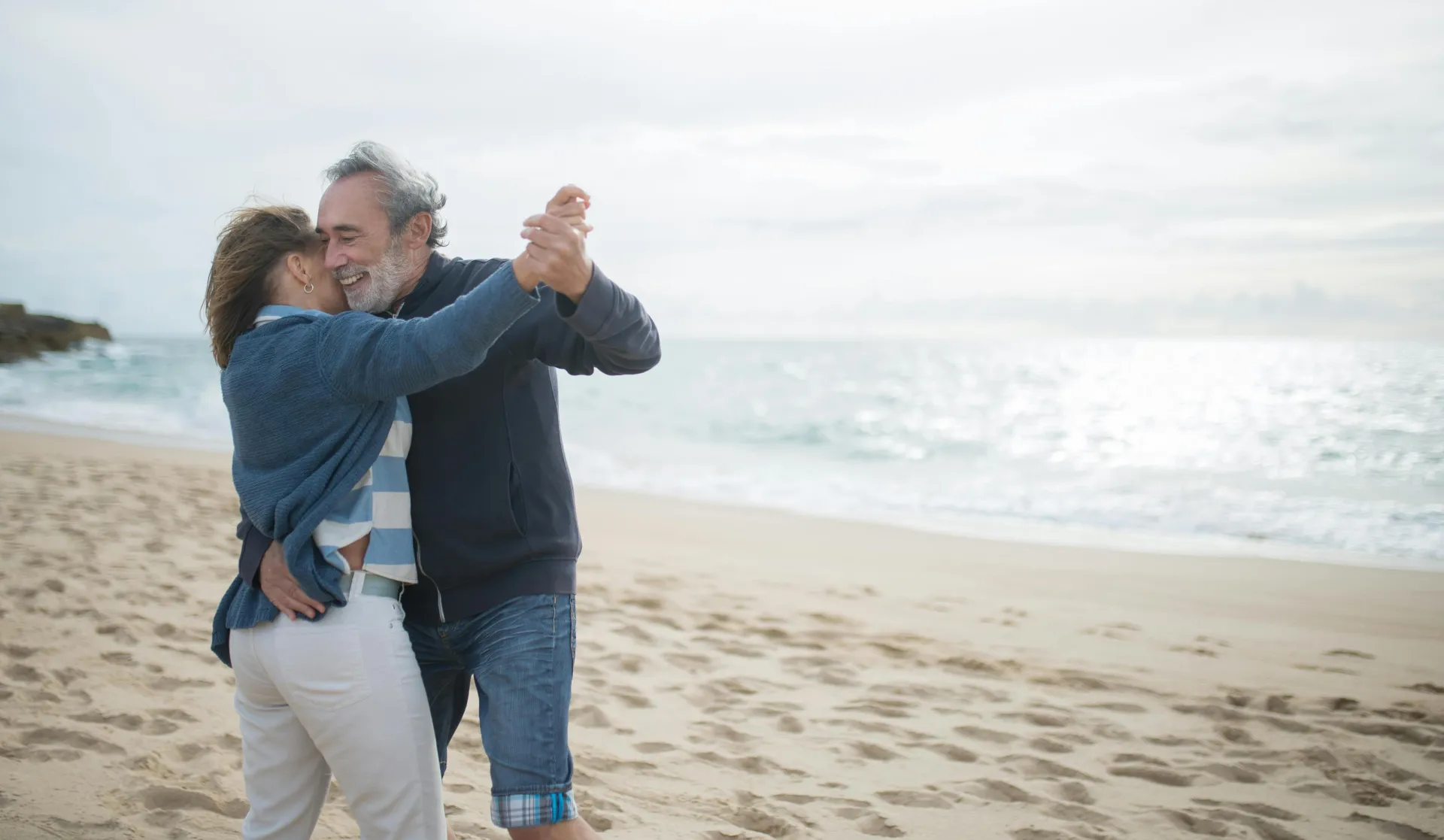 Happy couple dancing on a serene beach in Portugal, embracing love and nature.