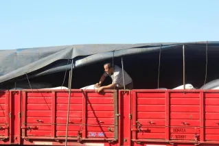 A man inspecting cargo on a red truck under sunny outdoors, exemplifying logistics