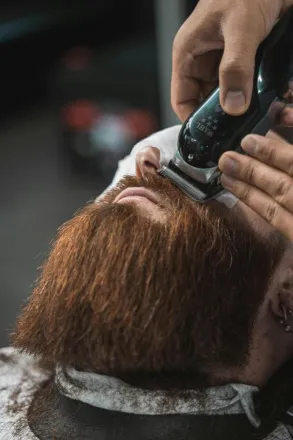 Close-up of a man receiving a precise beard trim at a barbershop.
