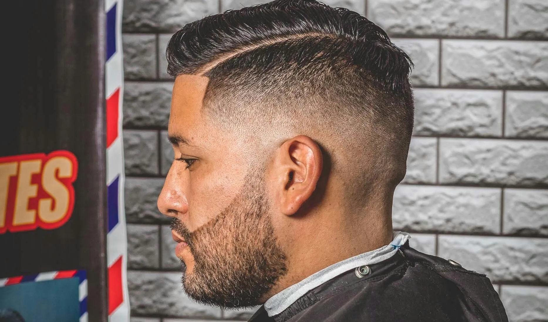 Profile view of a man with a stylish haircut in a barber shop.