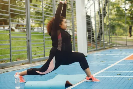African American woman doing yoga outdoors on a sunny day, emphasizing fitness and lifestyle.