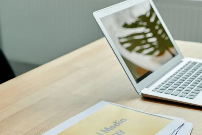 Close-up of social media strategy documents on a desk with a laptop, highlighting office planning.