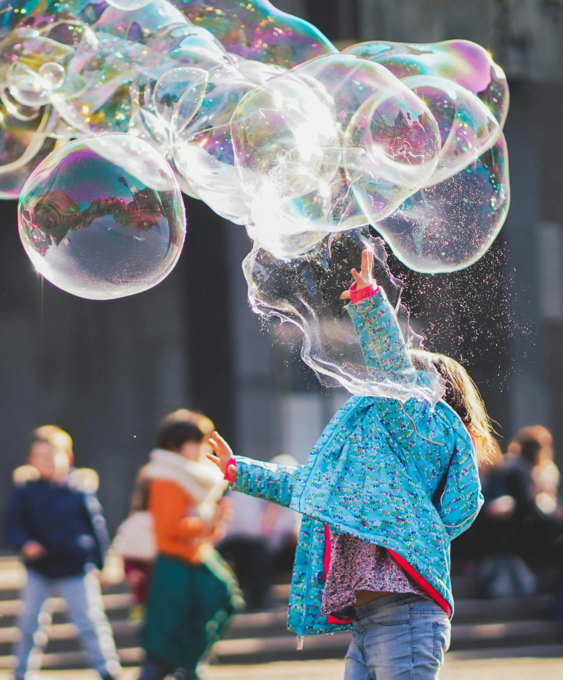 A child delights in chasing and popping giant bubbles in an outdoor setting.