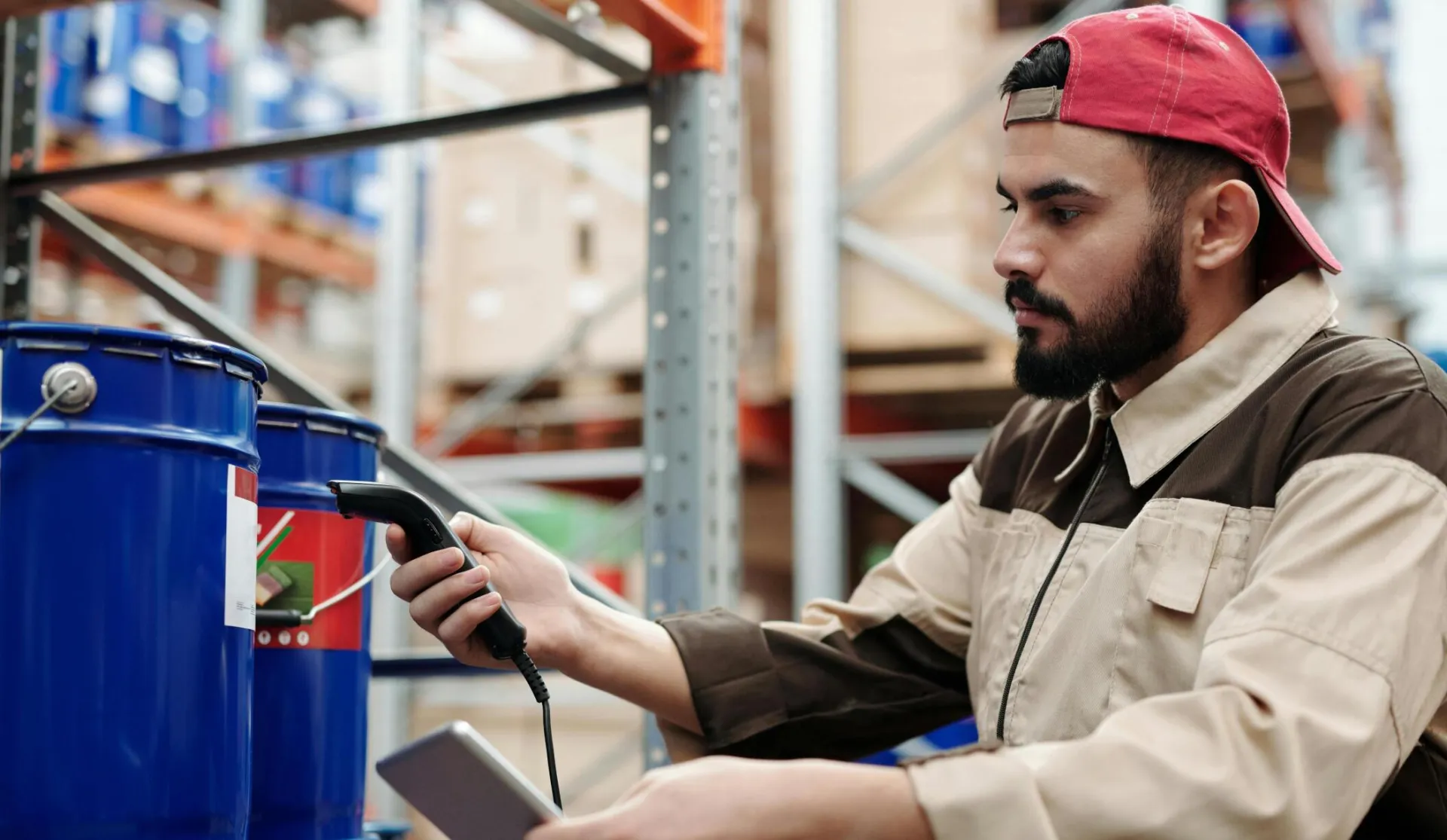 Male warehouse worker scanning barrels with a tablet for inventory management.