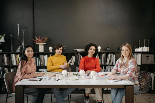 A diverse team of young adults working together in a creative office space, discussing and collaborating on projects.