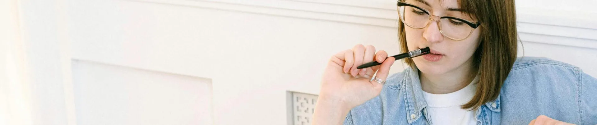 Woman working thoughtfully in home office, reflecting on ideas with laptop and notebook.