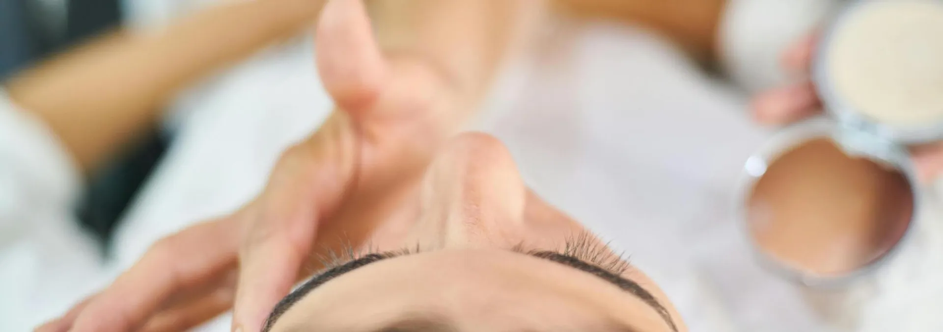 Close-up view of a professional makeup artist applying cosmetics indoors, highlighting beauty and skin care.