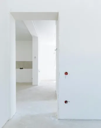 Bright unfinished room with white walls and exposed wiring, showcasing modern interior design potential.
