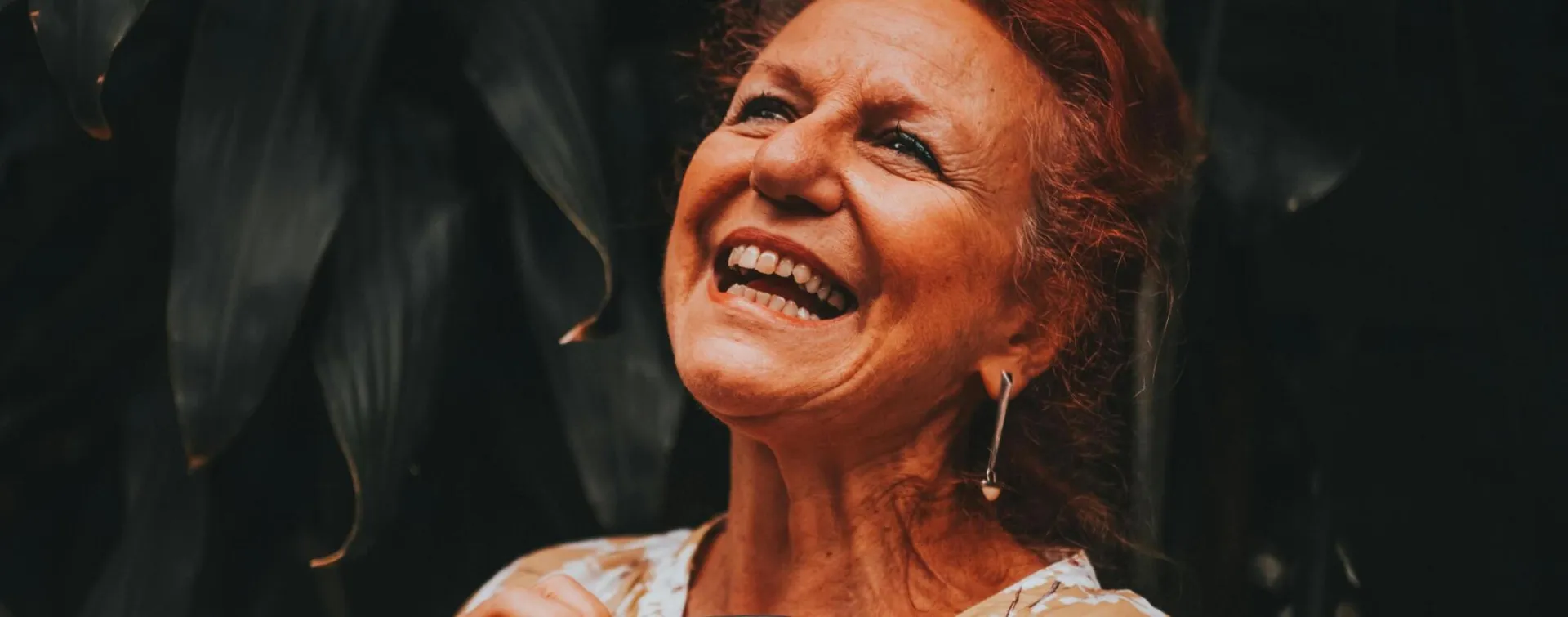 Cheerful elderly woman smiling and enjoying nature outdoors.