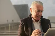 Senior businessman with tablet outdoors, adjusting eyeglasses, and reviewing business data.